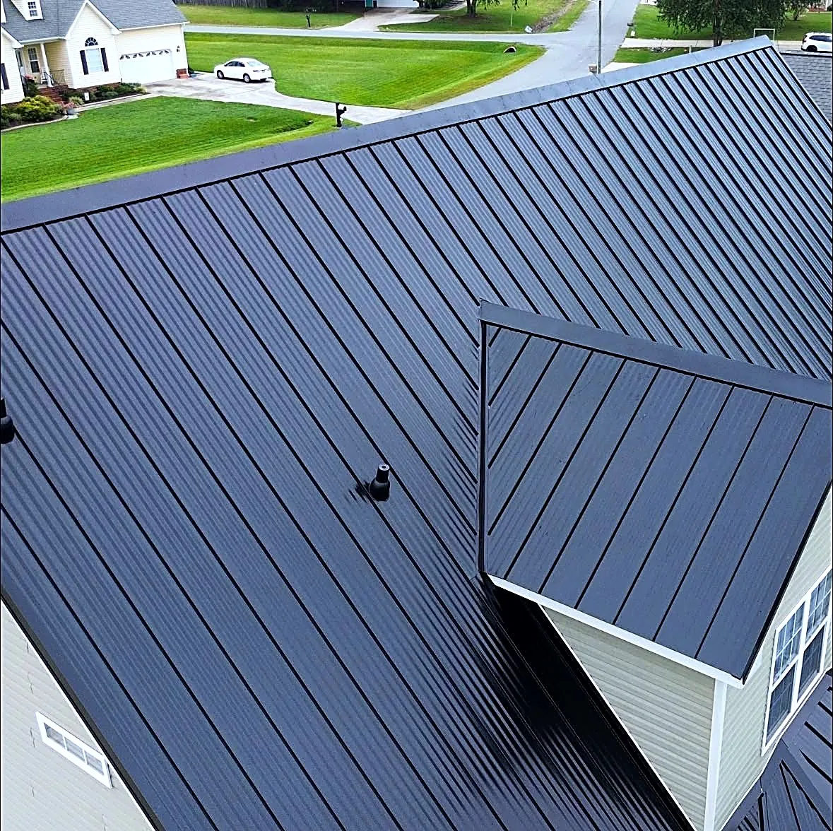 Close aerial view of black standing-seam metal panels and a color-matched pipe boot