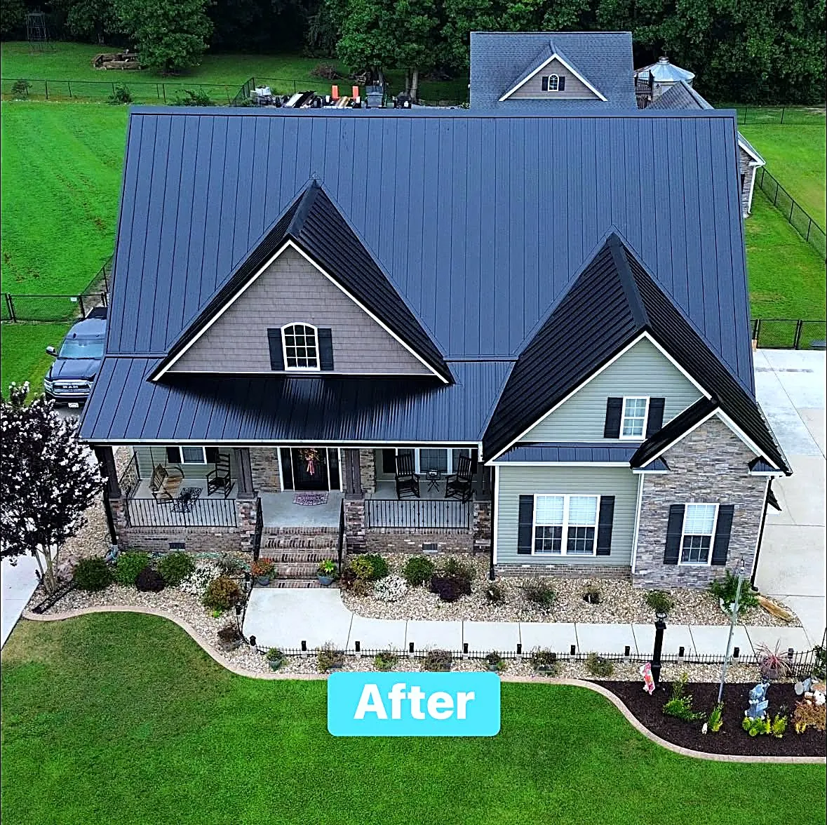 Aerial after photo of the same home with a new black standing-seam metal roof