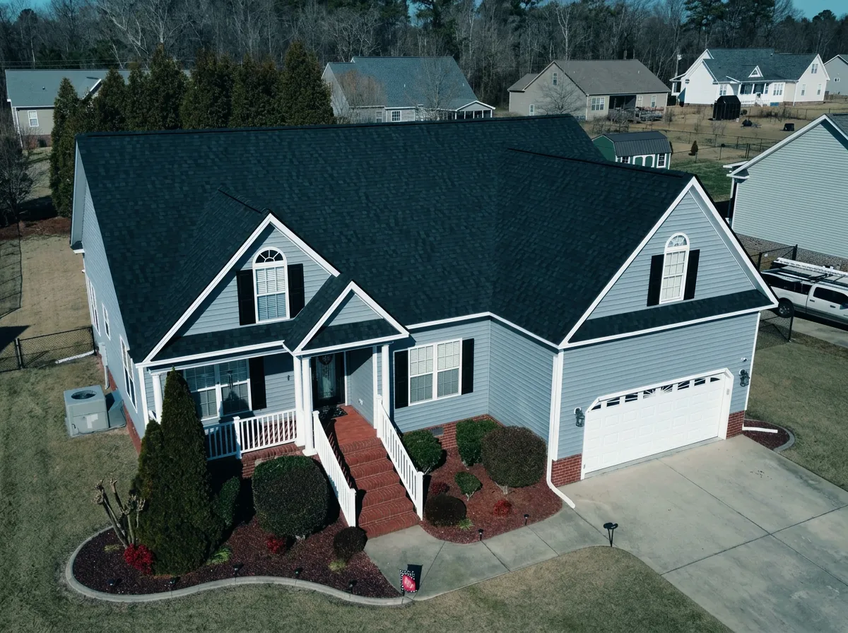 Completed charcoal shingle roof on a blue home with white trim — roofing near Dudley, NC
